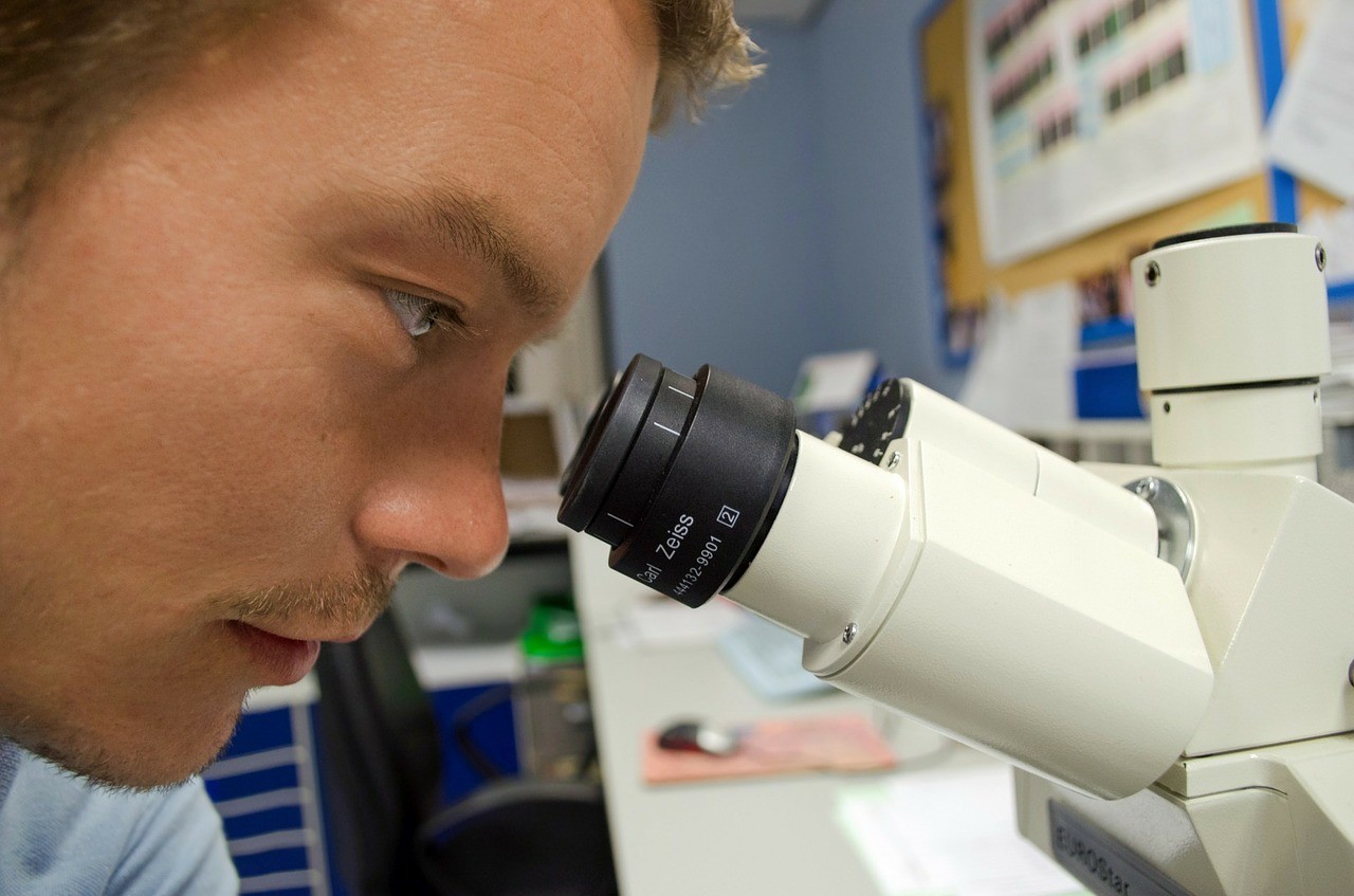Man looking at something with a microscope.
